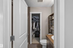 Bathroom featuring a single vanity with an integrated sink, a built-in toilet, and open shelving - 