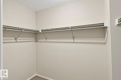 Built-in closet shelving system with white wire racks and hanging rods, beige wall paint, and wood-finish flooring - 