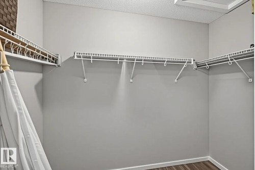Walk-in closet featuring wire shelving, white wall paint, wood-finish flooring, and white trim - #53 603 Watt Bv Sw, Edmonton, AB - Indoor With Storage