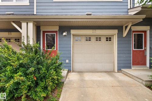 Exterior featuring blue horizontal siding, a light-colored garage door with window inserts, and a concrete driveway - #53 603 Watt Bv Sw, Edmonton, AB - Outdoor With Exterior