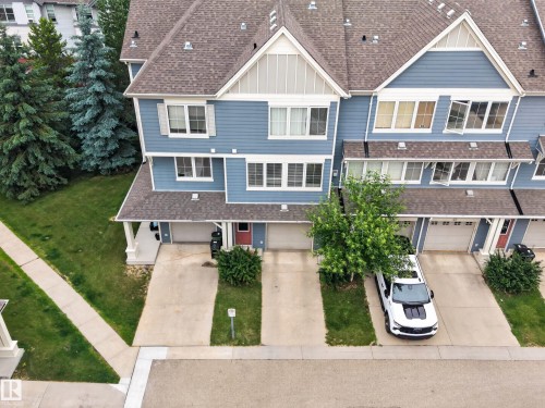 Blue multi-level townhouse exterior featuring gabled roofs, multiple windows, and a dedicated driveway - #53 603 Watt Bv Sw, Edmonton, AB - Outdoor With Facade