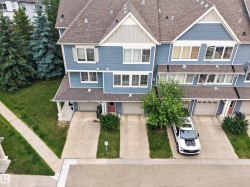 Blue multi-level townhouse exterior featuring gabled roofs, multiple windows, and a dedicated driveway - 