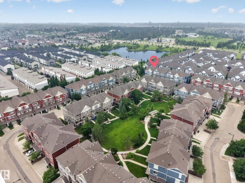 Aerial perspective showcasing a residential community with multi-story townhomes featuring varied exterior finishes and sloped roofs - #53 603 Watt Bv Sw, Edmonton, AB - Outdoor With View