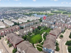 Aerial perspective showcasing a residential community with multi-story townhomes featuring varied exterior finishes and sloped roofs - 