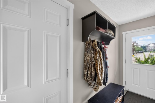Entryway with a multi-paneled white door and a dark wood-finish storage unit featuring a top shelf, coat hooks, and a lower shoe rack - #53 603 Watt Bv Sw, Edmonton, AB - Indoor Photo Showing Other Room