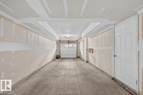 Spacious two-car garage with a concrete floor, white paneled door, and overhead lighting - #53 603 Watt Bv Sw, Edmonton, AB - Indoor