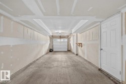 Spacious two-car garage with a concrete floor, white paneled door, and overhead lighting - 
