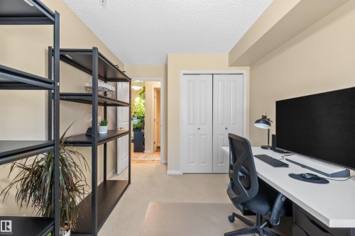 Built-in bi-fold closet doors, neutral carpet flooring, and painted walls - #209 103 Ambleside Drive Sw, Edmonton, AB - Indoor Photo Showing Office