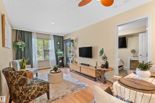 Wood-finish flooring, a ceiling fan with integrated lighting, and a large window with blinds - #209 103 Ambleside Drive Sw, Edmonton, AB - Indoor Photo Showing Living Room