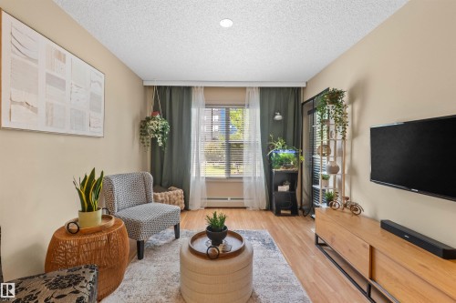 Wood-finish flooring, recessed ceiling light, window with blinds, and light-toned wall paint - #209 103 Ambleside Drive Sw, Edmonton, AB - Indoor Photo Showing Living Room