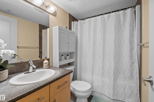 Built-in wood-finish vanity with an integrated sink and brushed nickel faucet - #209 103 Ambleside Drive Sw, Edmonton, AB - Indoor Photo Showing Bathroom