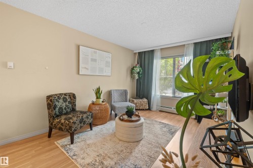 Wood-finish flooring, light-colored walls, and a window with blinds and drapes - #209 103 Ambleside Drive Sw, Edmonton, AB - Indoor Photo Showing Living Room