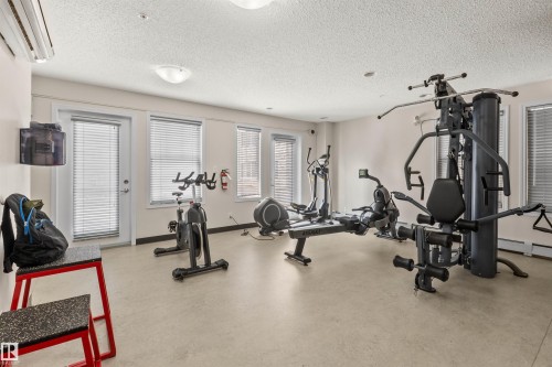 Dedicated fitness area featuring multiple exercise machines, light-colored flooring, and recessed lighting - #209 103 Ambleside Drive Sw, Edmonton, AB - Indoor Photo Showing Gym Room