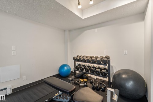 Recessed ceiling with track lighting illuminates this dedicated exercise space featuring hard-wearing floor surfacing - #209 103 Ambleside Drive Sw, Edmonton, AB - Indoor Photo Showing Office