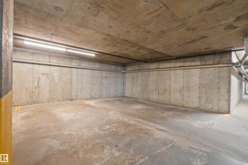 Concrete parking stall with exposed ceiling, integrated lighting, and painted support columns - #209 103 Ambleside Drive Sw, Edmonton, AB - Indoor Photo Showing Garage