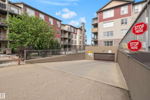 Multi-story building exterior with red siding and stone accents - #209 103 Ambleside Drive Sw, Edmonton, AB - Outdoor