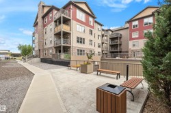 Multi-story building featuring balconies, stone accents, and a paved courtyard with benches - 
