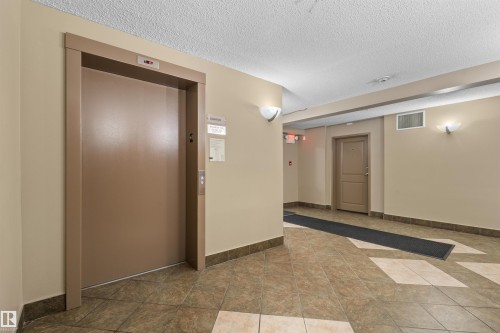 Elevator access with call buttons, wall-mounted sconces, and neutral-toned wall paint - #209 103 Ambleside Drive Sw, Edmonton, AB - Indoor Photo Showing Other Room