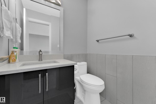 Contemporary vanity with a light-colored countertop and dark cabinetry, featuring an integrated rectangular sink and a single-handle faucet - 9329 Connors Road Nw, Edmonton, AB - Indoor Photo Showing Bathroom