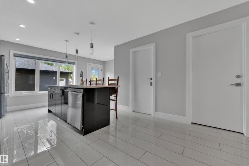 Contemporary kitchen featuring a central island with integrated dishwasher, pendant lighting, and light wood-finish countertop - 9329 Connors Road Nw, Edmonton, AB - Indoor Photo Showing Kitchen