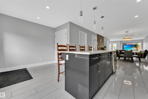 Spacious kitchen island with glossy dark cabinetry, an undermount sink, and a built-in wine cooler - 9329 Connors Road Nw, Edmonton, AB - Indoor Photo Showing Kitchen