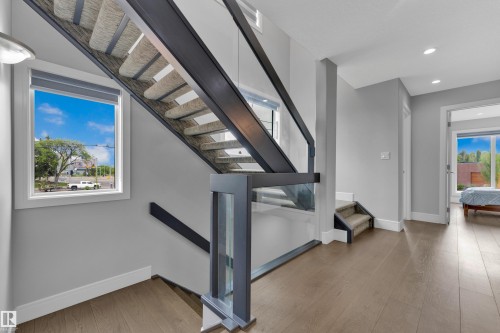 Modern staircase featuring an open tread design, dark metal framing, and glass panel railings - 9329 Connors Road Nw, Edmonton, AB - Indoor Photo Showing Other Room