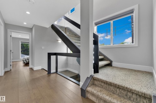 Modern staircase featuring black metal railings and clear glass panels - 9329 Connors Road Nw, Edmonton, AB - Indoor Photo Showing Other Room