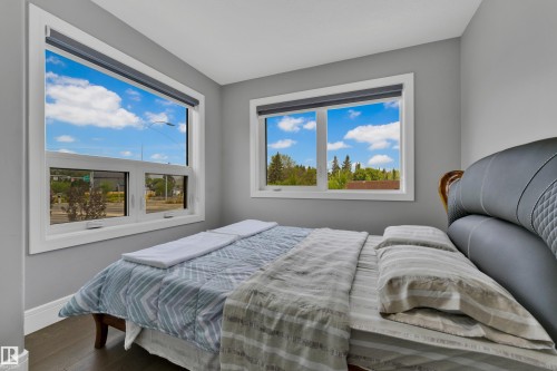 Bright interior space featuring two large windows with white trim, wood-finish flooring, and light gray wall paint - 9329 Connors Road Nw, Edmonton, AB - Indoor Photo Showing Bedroom