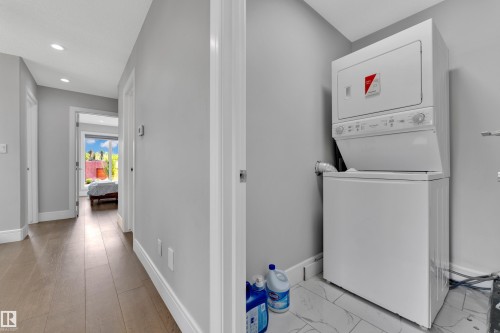 Dedicated laundry area featuring a stackable washer and dryer unit, complemented by tile flooring - 9329 Connors Road Nw, Edmonton, AB - Indoor Photo Showing Laundry Room