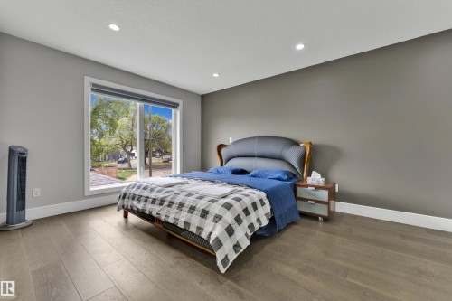 Spacious room featuring wood-finish flooring, a large window, recessed lighting, and a two-tone wall color scheme - 9329 Connors Road Nw, Edmonton, AB - Indoor Photo Showing Bedroom