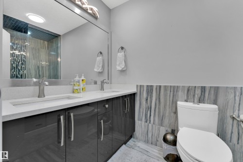Dual vanity with integrated rectangular sinks and brushed nickel faucets set into a light-toned countertop - 9329 Connors Road Nw, Edmonton, AB - Indoor Photo Showing Bathroom