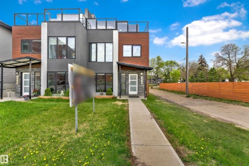 Modern townhouse exterior featuring a multi-level facade with wood-finish siding and dark gray stucco - 9329 Connors Road Nw, Edmonton, AB - Outdoor