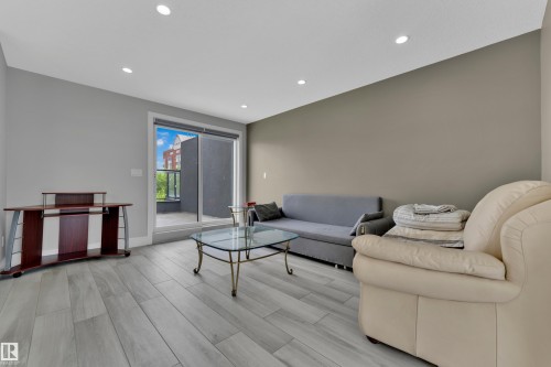 Spacious living area featuring light wood-finish flooring, recessed lighting, and a sliding glass door providing access to an outdoor balcony - 9329 Connors Road Nw, Edmonton, AB - Indoor