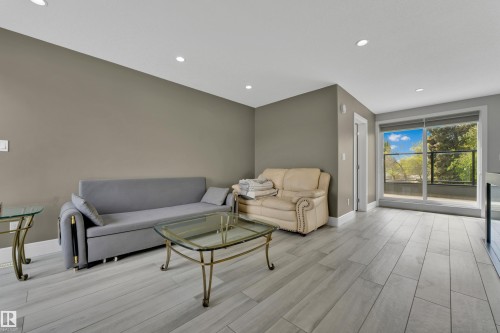 Spacious living area featuring light wood-finish flooring, recessed lighting, and direct patio access through a large sliding glass door - 9329 Connors Road Nw, Edmonton, AB - Indoor