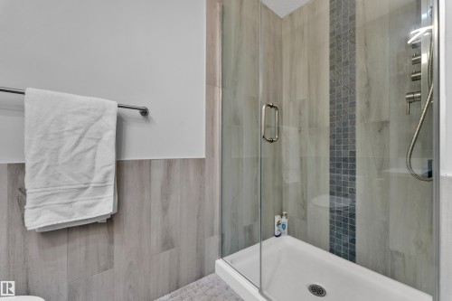 Enclosed glass shower featuring a multi-function shower panel with brushed nickel fixtures - 9329 Connors Road Nw, Edmonton, AB - Indoor Photo Showing Bathroom