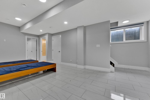 Spacious room featuring light gray walls, recessed lighting, white baseboards, and large format tiled flooring - 9329 Connors Road Nw, Edmonton, AB - Indoor Photo Showing Other Room