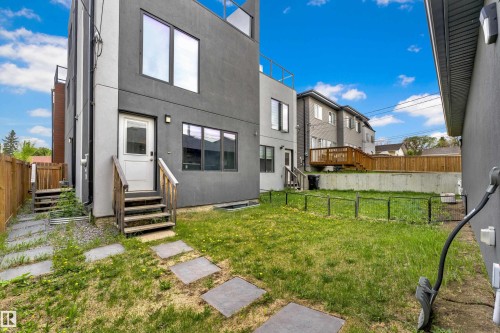 Rear exterior showcasing a private fenced yard with concrete stepping stones and a wooden fence boundary - 9329 Connors Road Nw, Edmonton, AB - Outdoor