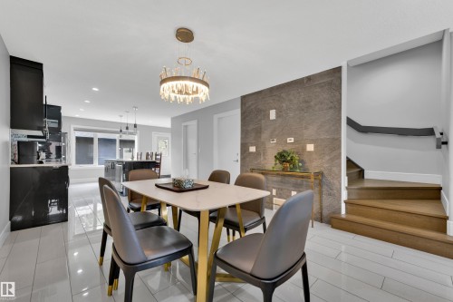 Dining area featuring a contemporary chandelier, large format tile flooring, and a stone accent wall - 9329 Connors Road Nw, Edmonton, AB - Indoor Photo Showing Dining Room