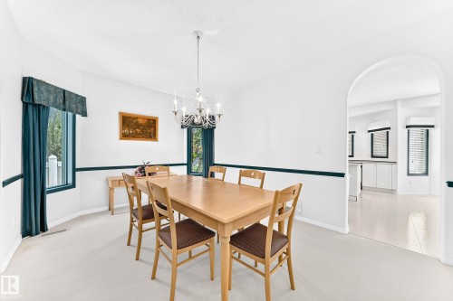 Archway entry, chandelier lighting, white walls, dark green trim, and windows with trim - 209 Carmichael Close Nw, Edmonton, AB - Indoor Photo Showing Dining Room