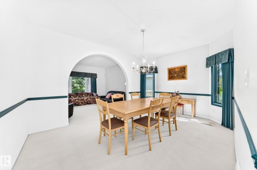 Archway entry, chandelier lighting fixture, bay window, painted trim, neutral wall tones - 209 Carmichael Close Nw, Edmonton, AB - Indoor Photo Showing Dining Room