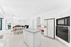 Kitchen featuring a central island, white cabinetry, integrated wall oven, and built-in microwave - 
