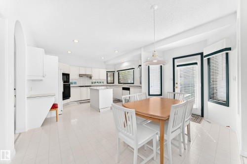 Open-concept kitchen and dining area featuring white cabinetry, a central island, recessed lighting, and multiple windows - 209 Carmichael Close Nw, Edmonton, AB - Indoor