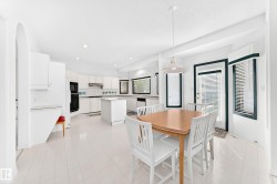 Open-concept kitchen and dining area featuring white cabinetry, a central island, recessed lighting, and multiple windows - 