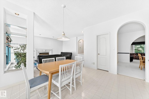 Arched doorways, tiled flooring, built-in shelving with glass panels, fireplace, and pendant lighting - 209 Carmichael Close Nw, Edmonton, AB - Indoor