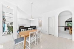 Arched doorways, tiled flooring, built-in shelving with glass panels, fireplace, and pendant lighting - 