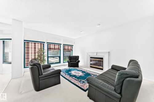Living area featuring a fireplace with a white mantel, multiple large windows, and recessed lighting - 209 Carmichael Close Nw, Edmonton, AB - Indoor Photo Showing Living Room With Fireplace