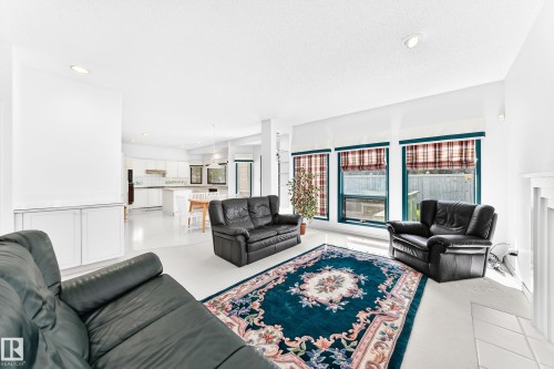 Bright open-concept living area with white walls and flooring, recessed lighting, and large windows - 209 Carmichael Close Nw, Edmonton, AB - Indoor Photo Showing Living Room With Fireplace