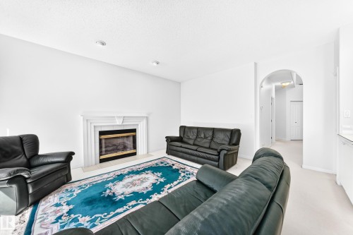 Living area featuring a fireplace with a white mantel, recessed lighting, and an arched entryway - 209 Carmichael Close Nw, Edmonton, AB - Indoor Photo Showing Living Room With Fireplace