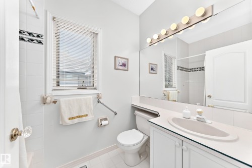 White vanity with integrated sink, expansive mirrored wall, and a window with blinds - 209 Carmichael Close Nw, Edmonton, AB - Indoor Photo Showing Bathroom
