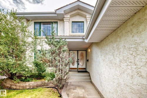 Stucco exterior with a peaked roofline, double entry doors with oval glass inserts, and a concrete pathway leading to the entrance - 209 Carmichael Close Nw, Edmonton, AB - Outdoor